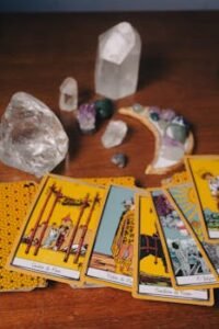 A collection of tarot cards and healing crystals arranged on a wooden surface for spiritual readings.